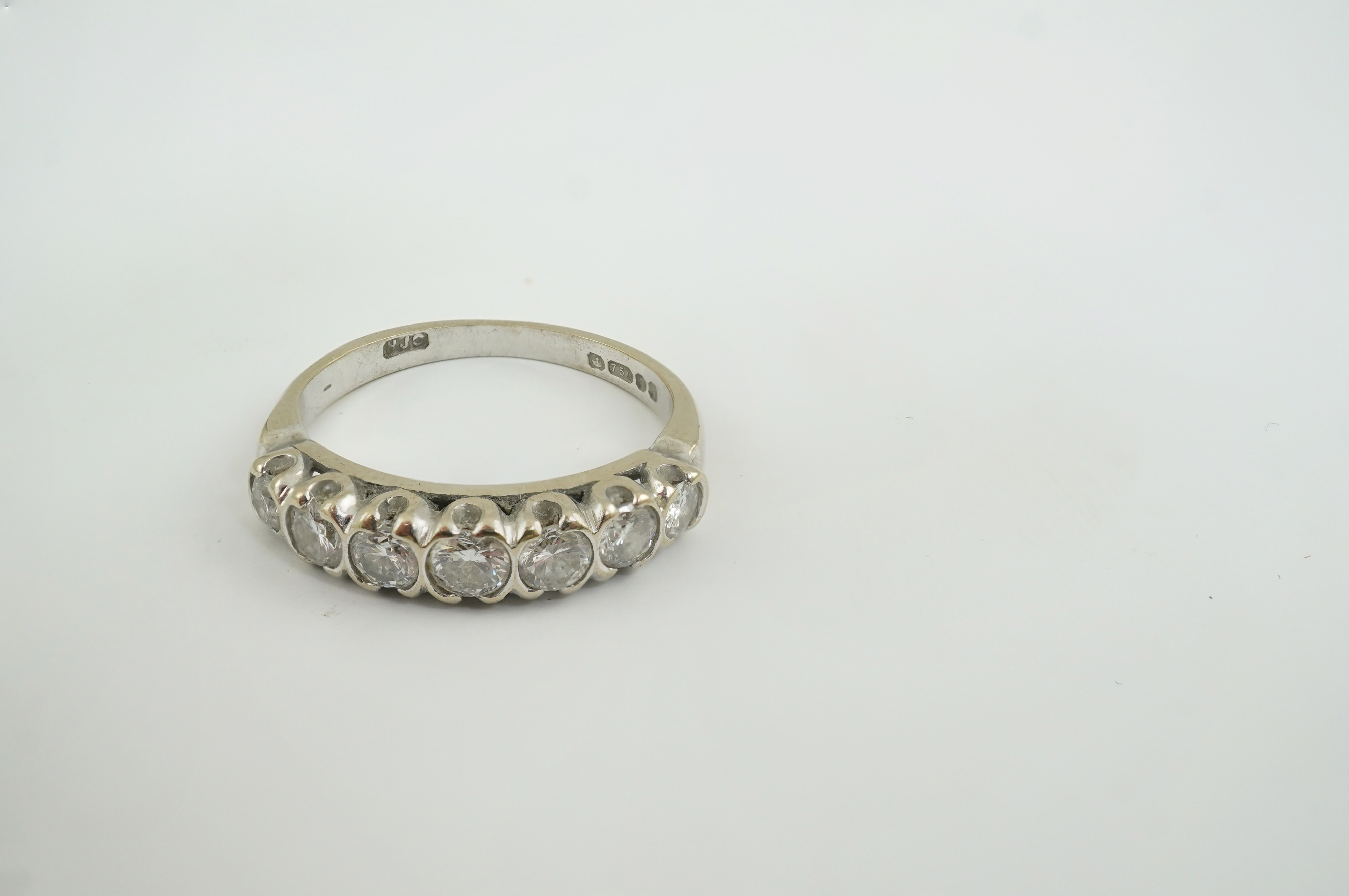 A modern 18ct white gold and graduated seven stone diamond set half hoop ring